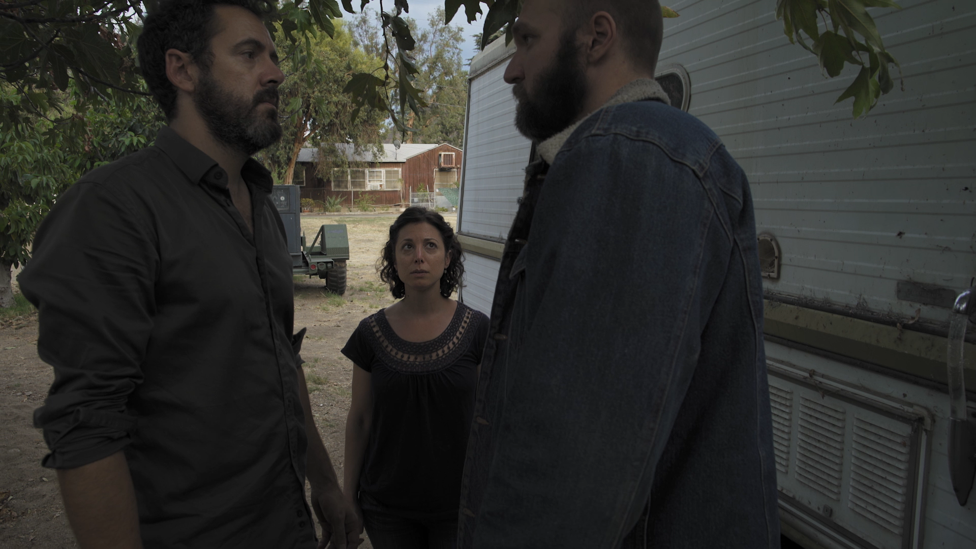 Two men facing each other and woman staring forward at them